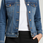 A blue denim jacket with a pointed collar, button front, and chest flap pockets, hanging in a retail store setting.