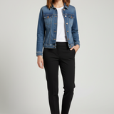 A blue denim jacket with a pointed collar, button front, and chest flap pockets, hanging in a retail store setting.